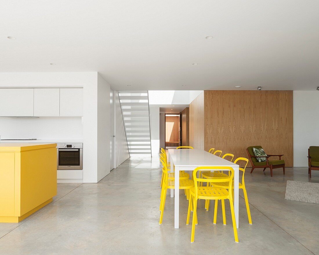 Minimalist interior with concrete floor, kitchen and dining area in yellow and white