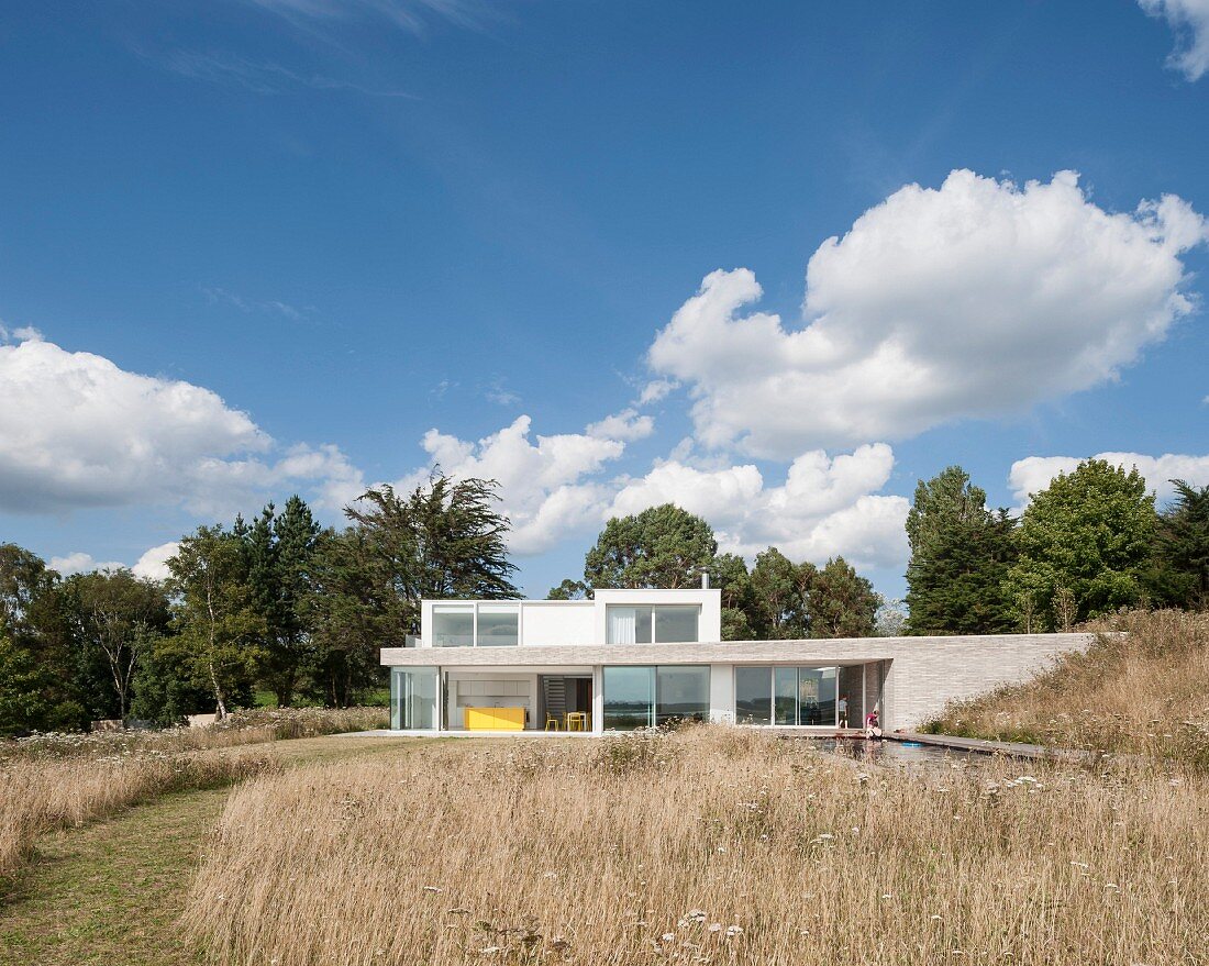 Blick über Wiese auf modernes Architektenhaus in Flachbauweise mit grosszügigen Festerfronten