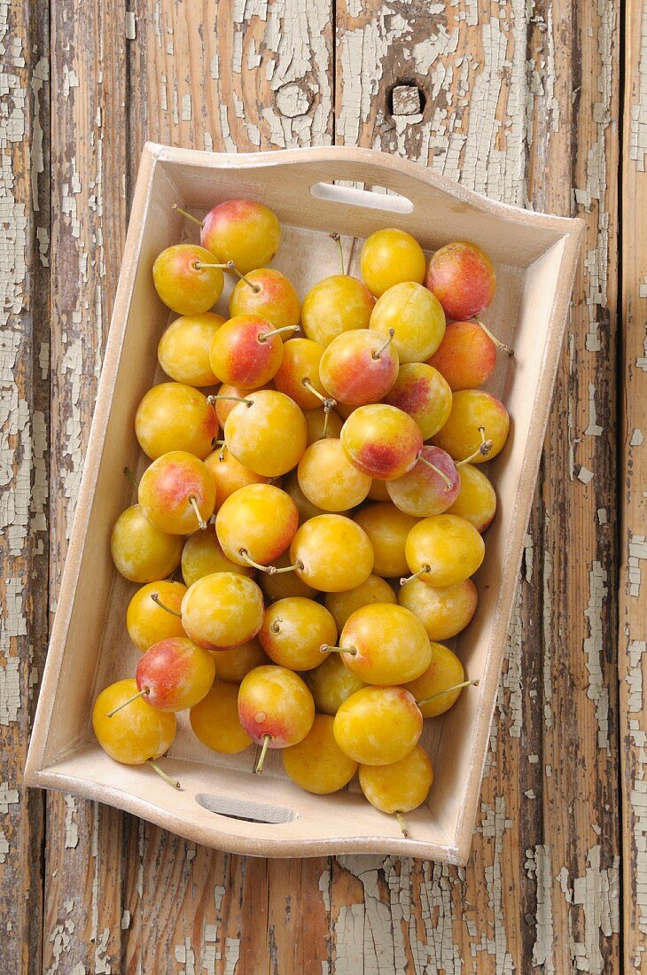 Fresh yellow plums on a wooden tray