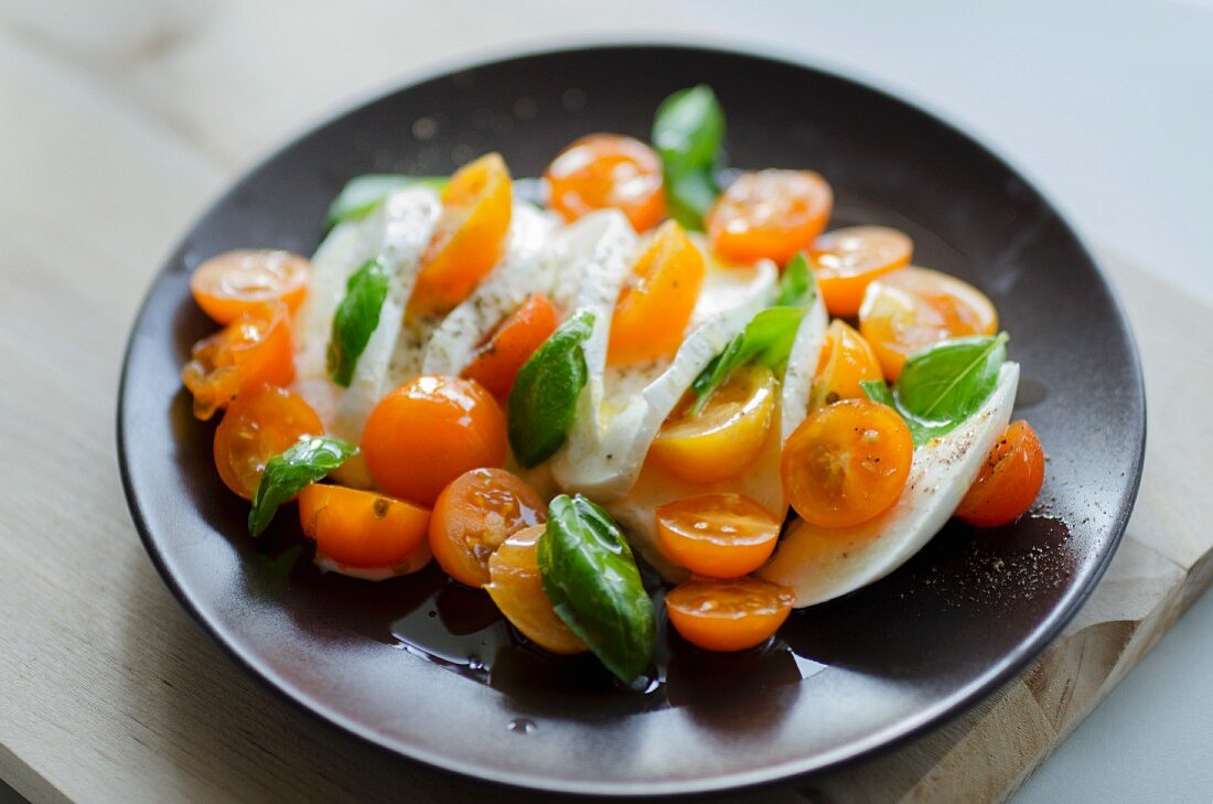 A salad of orange cocktail tomatoes, mozzarella and basil