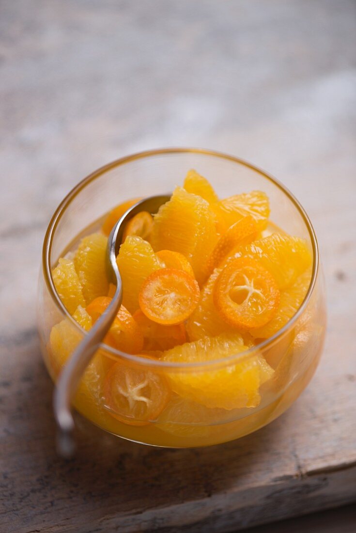 Fruit salad made of fresh oranges and kumquats in a glass bowl