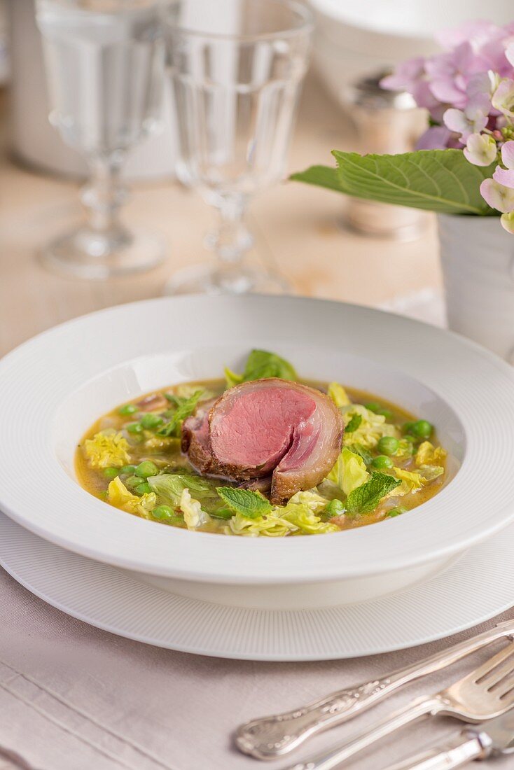 Pea soup with duck breast on a garden table