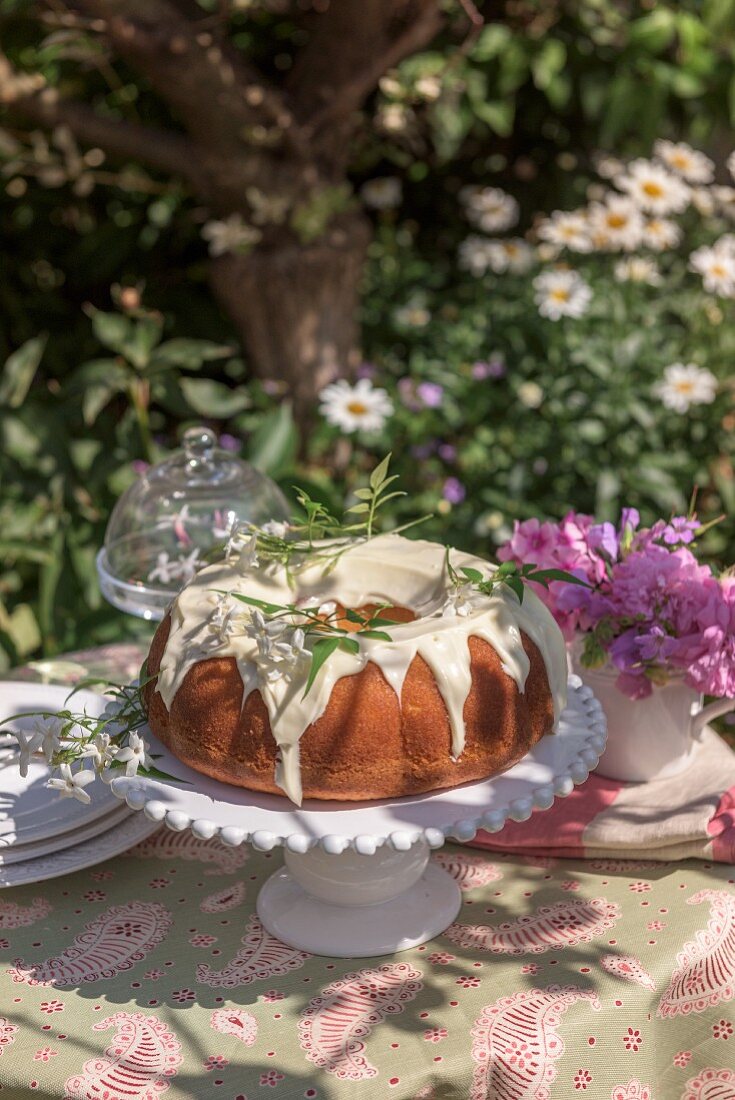 A Bundt cake with icing sugar on a garden table
