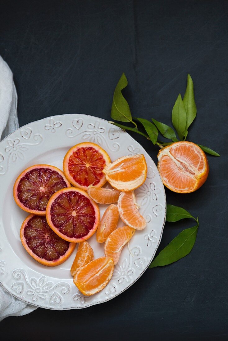Slices of blood oranges and mandarin segments on a white plate