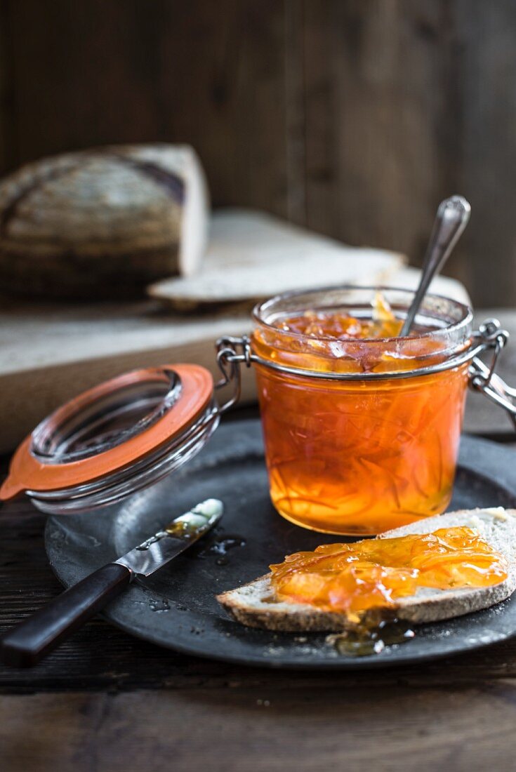 Orangenmarmelade im Bügelglas und auf Brot
