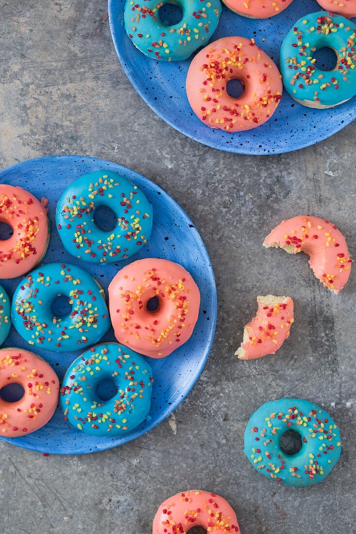 Donuts mit rosa und blauem Zuckerguss und Zuckerstreuseln (Draufsicht)
