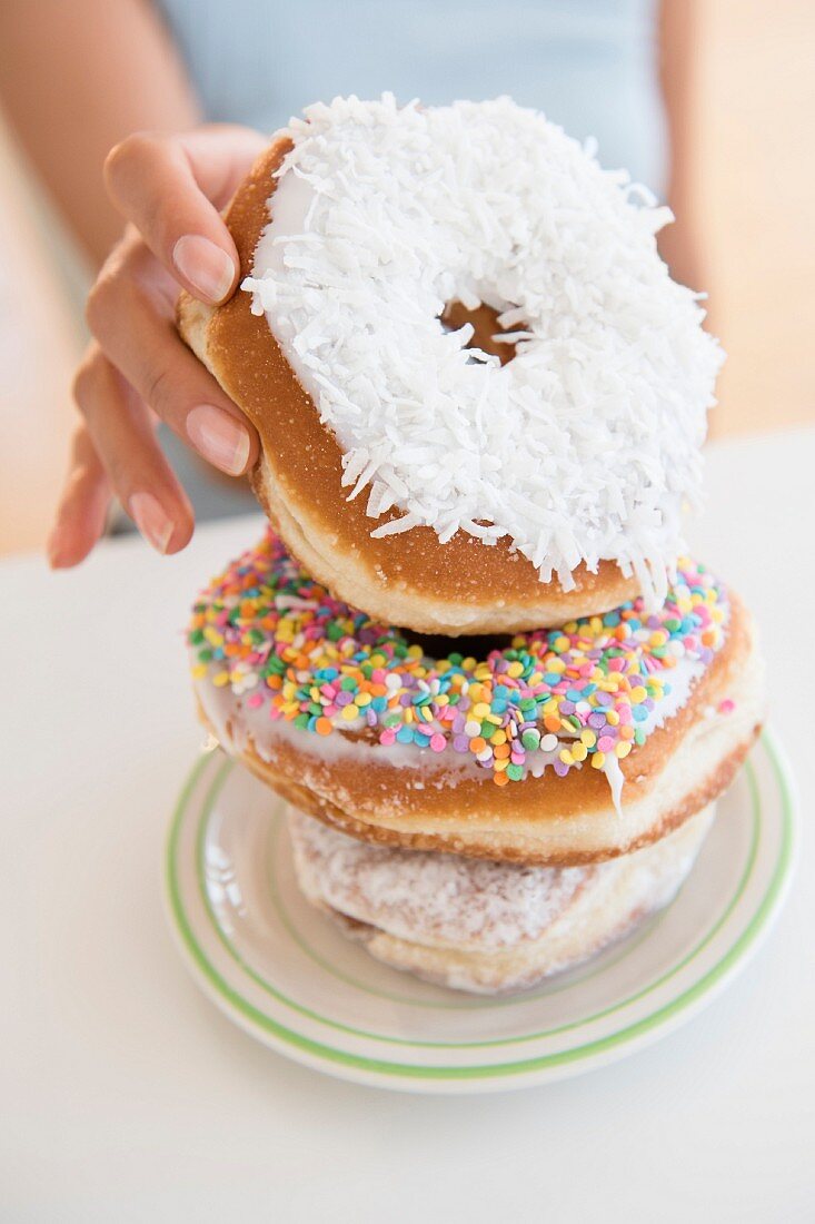 A woman taking a doughnut from a stack