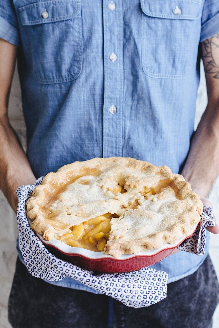 A man holding a peach pie