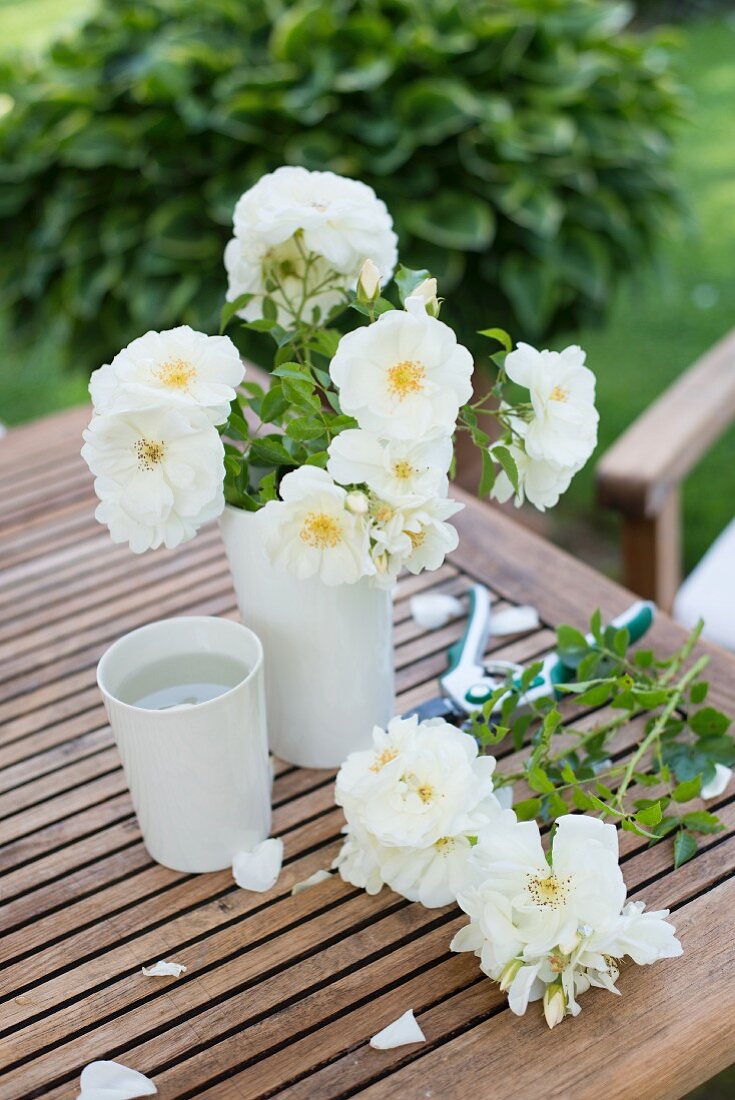 White roses in vase and on garden table