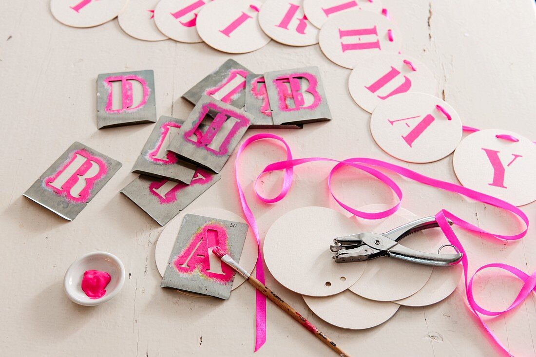 Alphabet stencils and letters on garland of card discs for birthday party