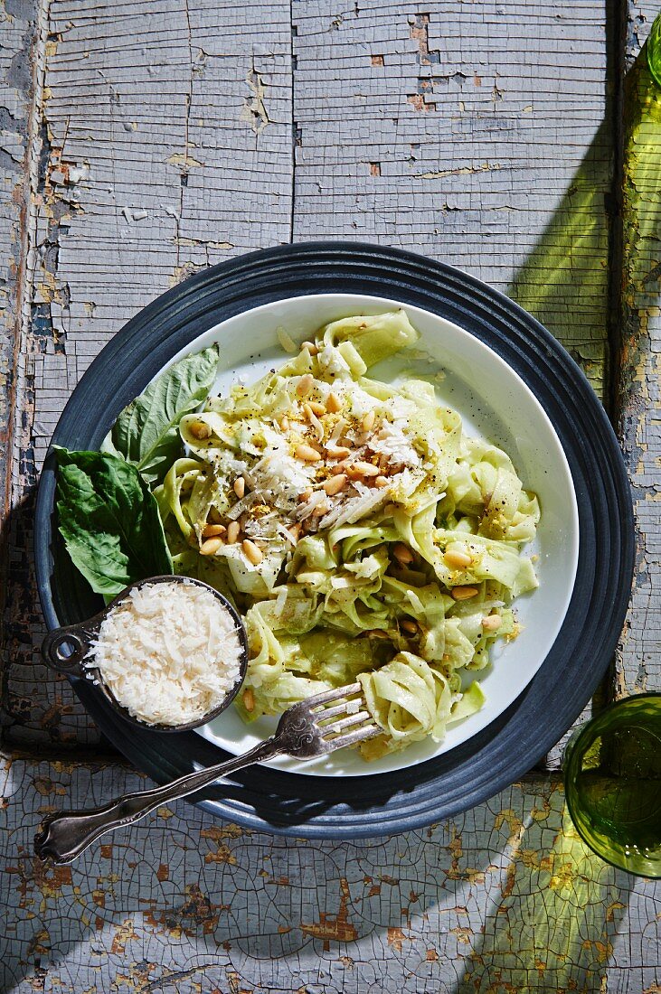 Courgette pasta with pesto and ricotta sauce garnished with pine nuts and grated Parmesan cheese