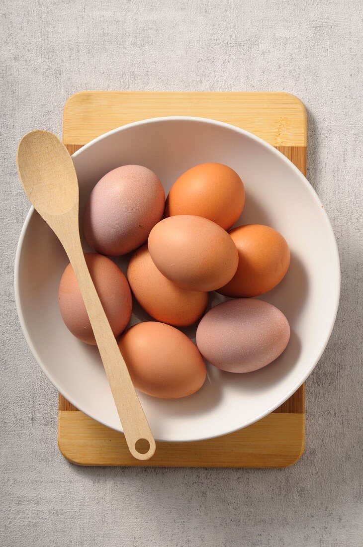 Frische Eier in Schüssel mit Kochlöffel