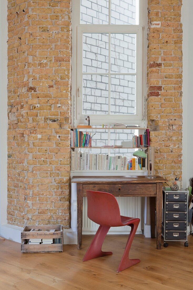Old desk below window flanked by brick walls
