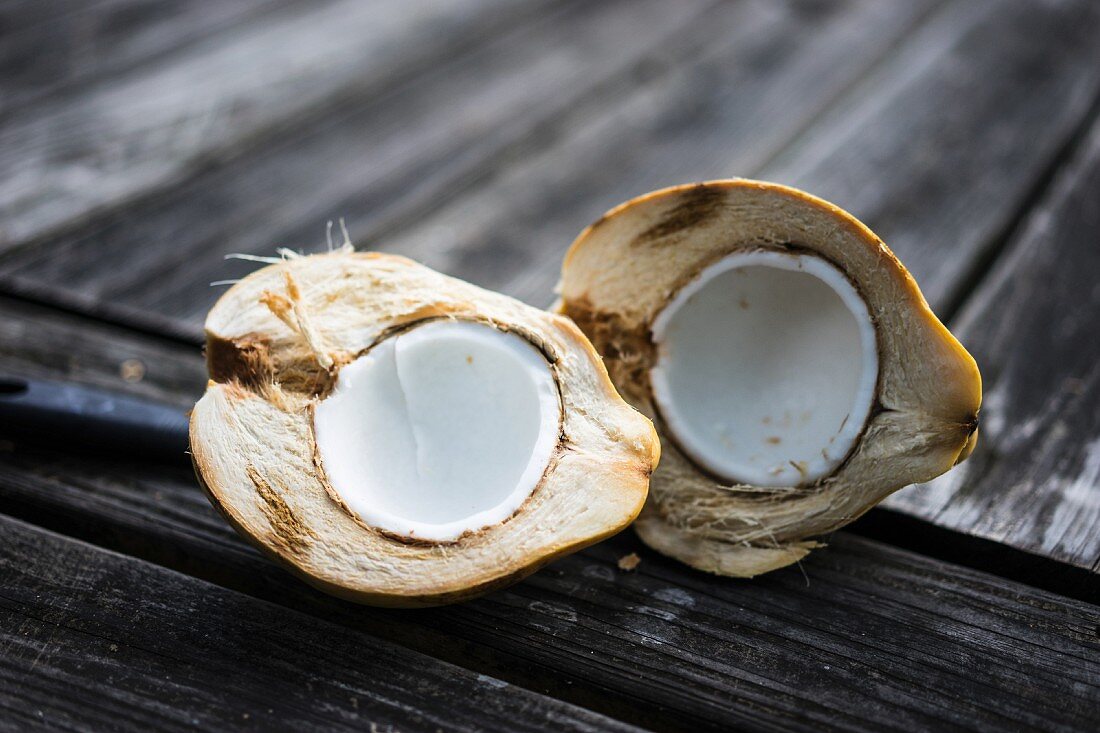 A halved coconut on a wooden surface