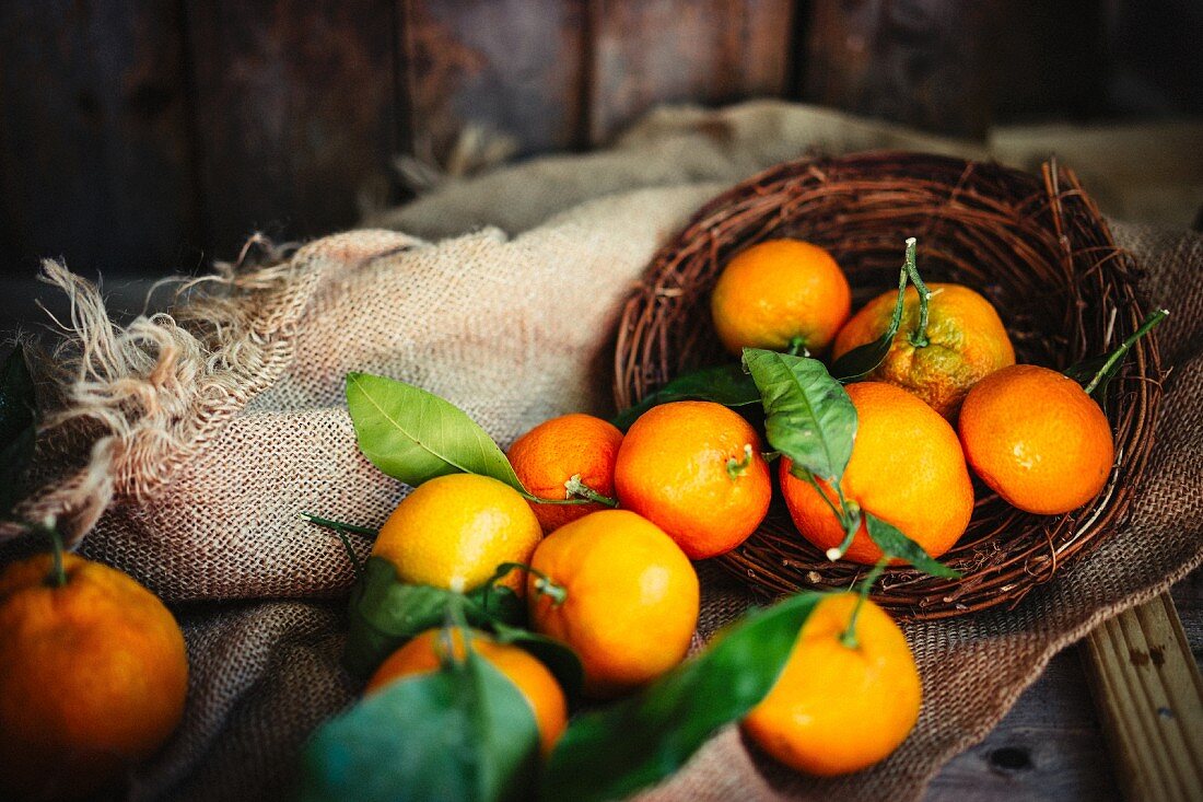 Mandarins with leaves in a basket on a rustic wooden surface