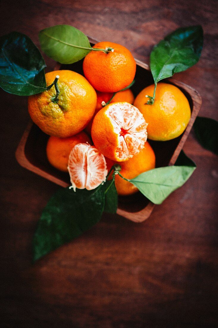 Mandarins with leaves on a rustic wooden surface