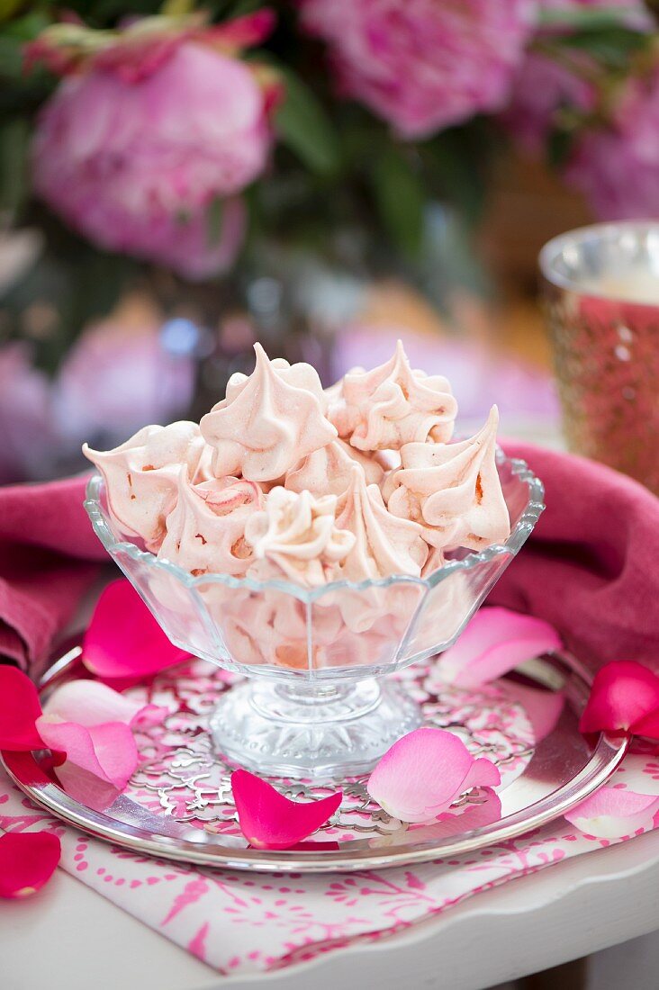 Raspberry meringues in a glass bowl on a table outside