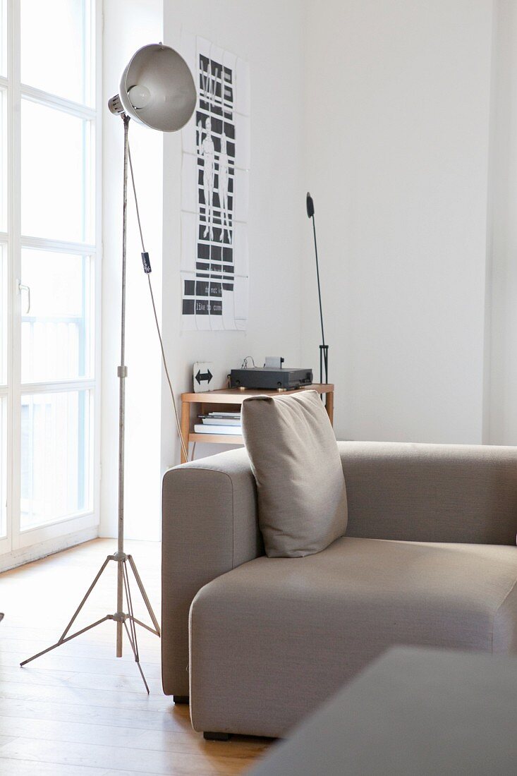 Industrial lamp next to grey sofa in urban loft apartment