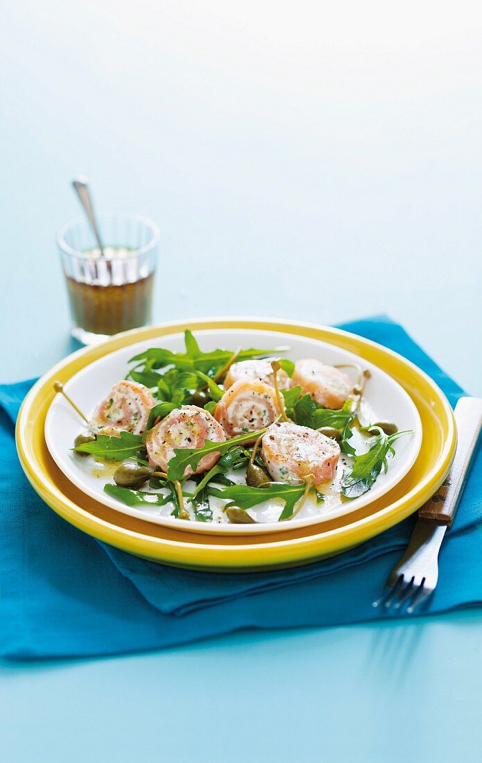 Smoked salmon rolls filled with cream cheese on a bed of rocket with capers