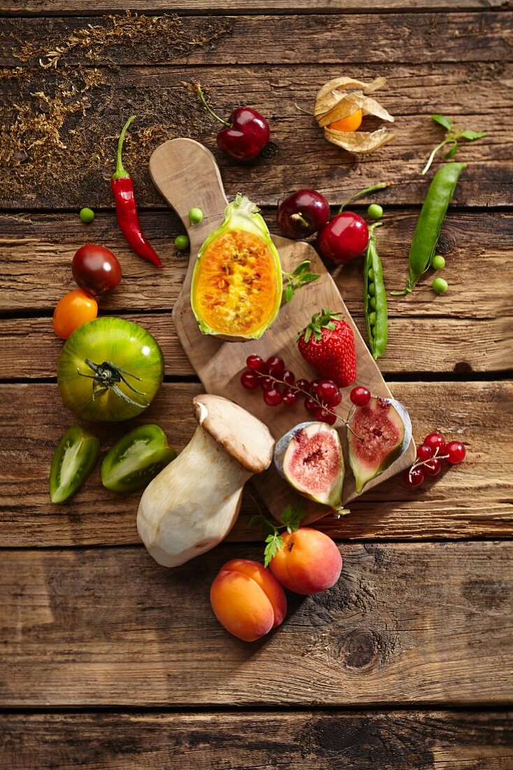 An arrangement of fruit, vegetables and mushrooms on a wooden surface