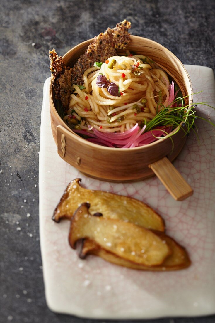 Raw kohlrabi spaghetti with bean sprouts and king trumpet mushrooms in soy sauce with sesame seed crackers (Asia)