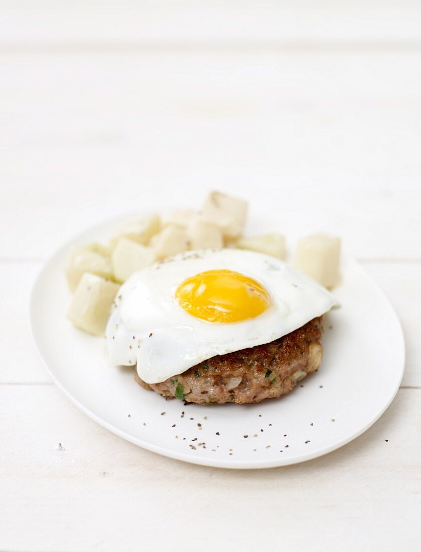 A burger topped with a fried egg served with kohlrabi