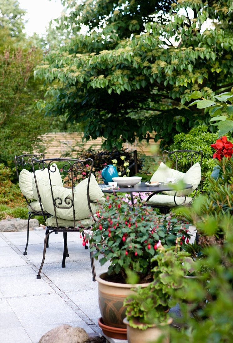 Black metal chairs with pale seat cushions around round table on terrace