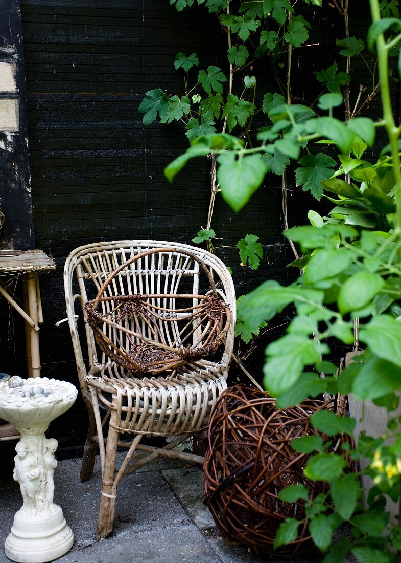 Vintage Rattanstuhl und Korb vor Holzwand auf Gartenterrasse