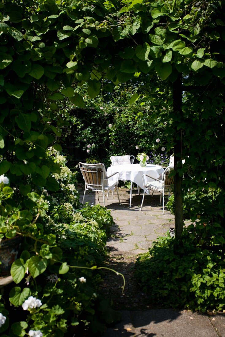View of romantic seating area with table and chairs in summery arbour