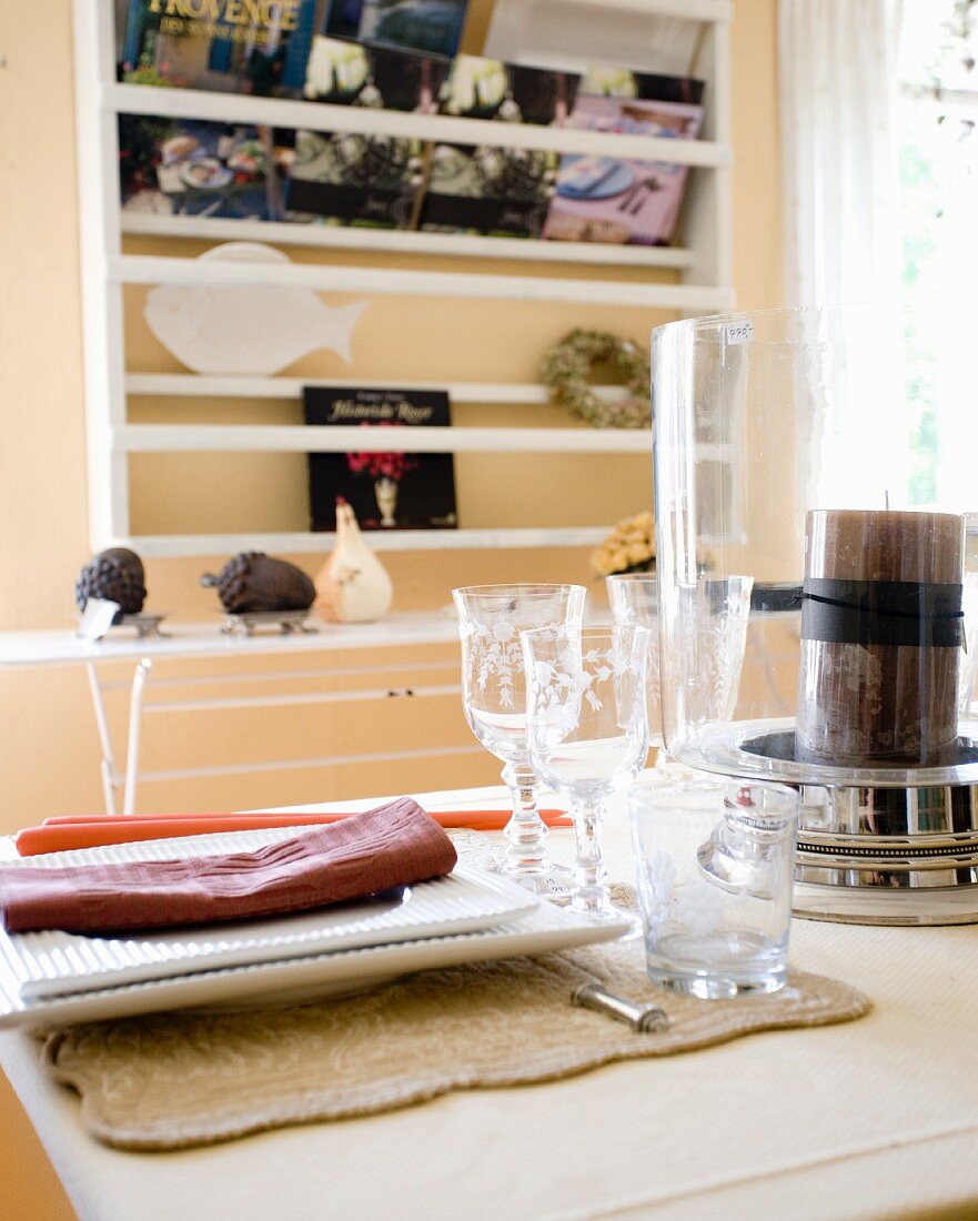 White plates, crystal glasses and candle on table