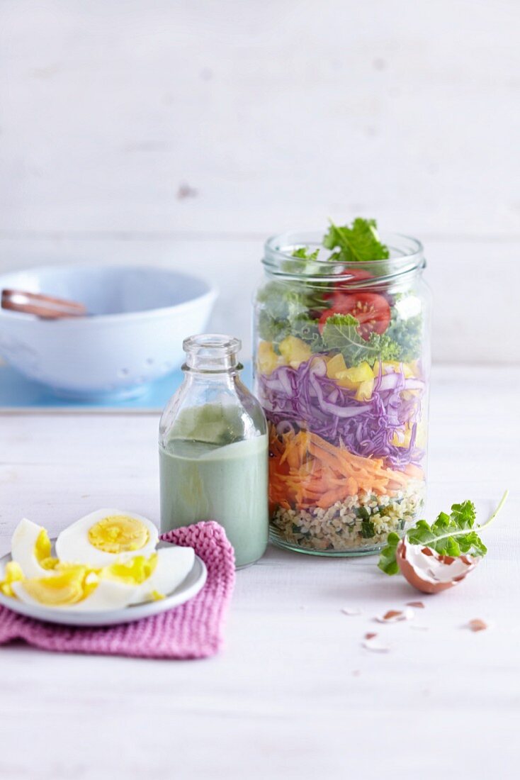 A layered rainbow salad in a jar with an avocado dressing