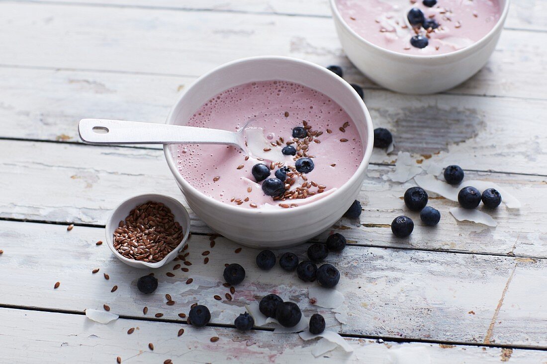 A bowl of raspberry smoothie with blueberries and flaxseeds