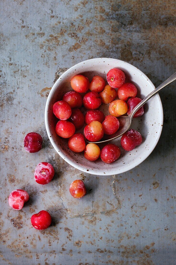 A bowl of frozen cherries on a rusty metal surface