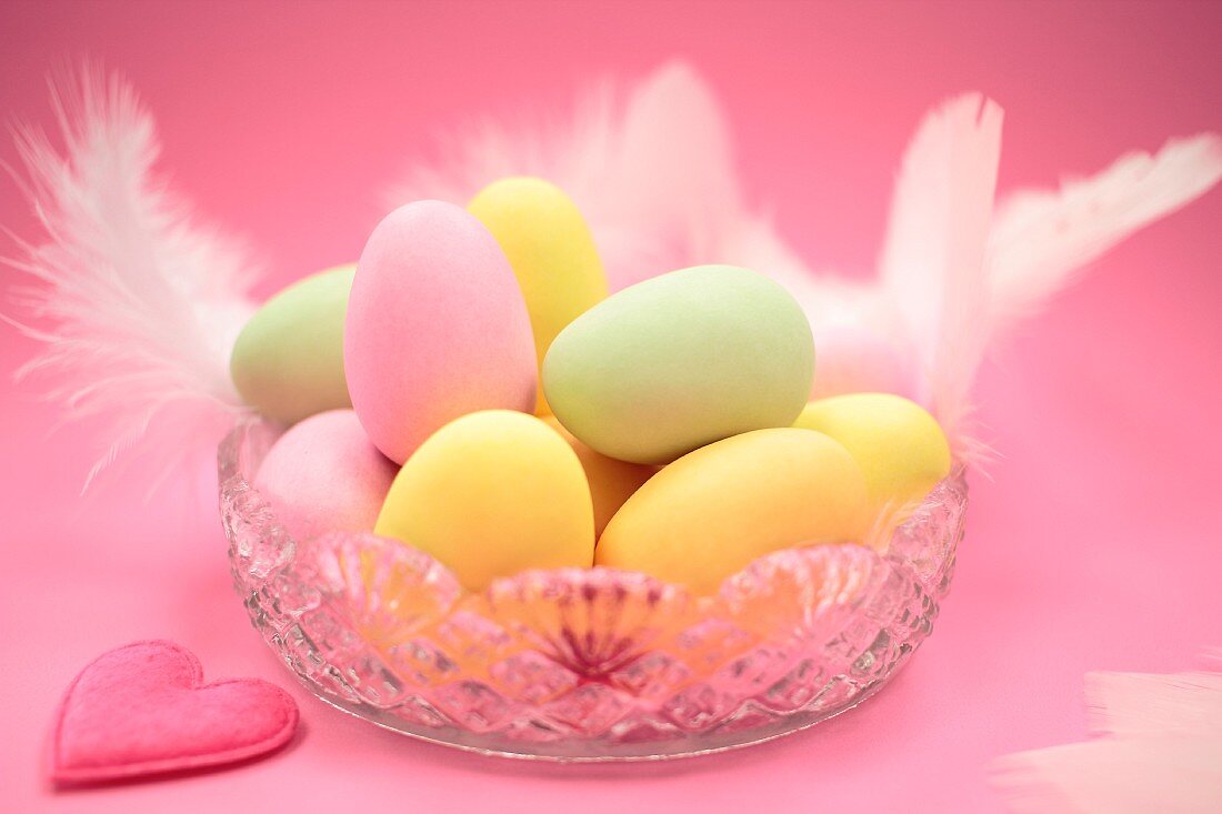 Pastel coloured Easter eggs with feathers in a glass bowl