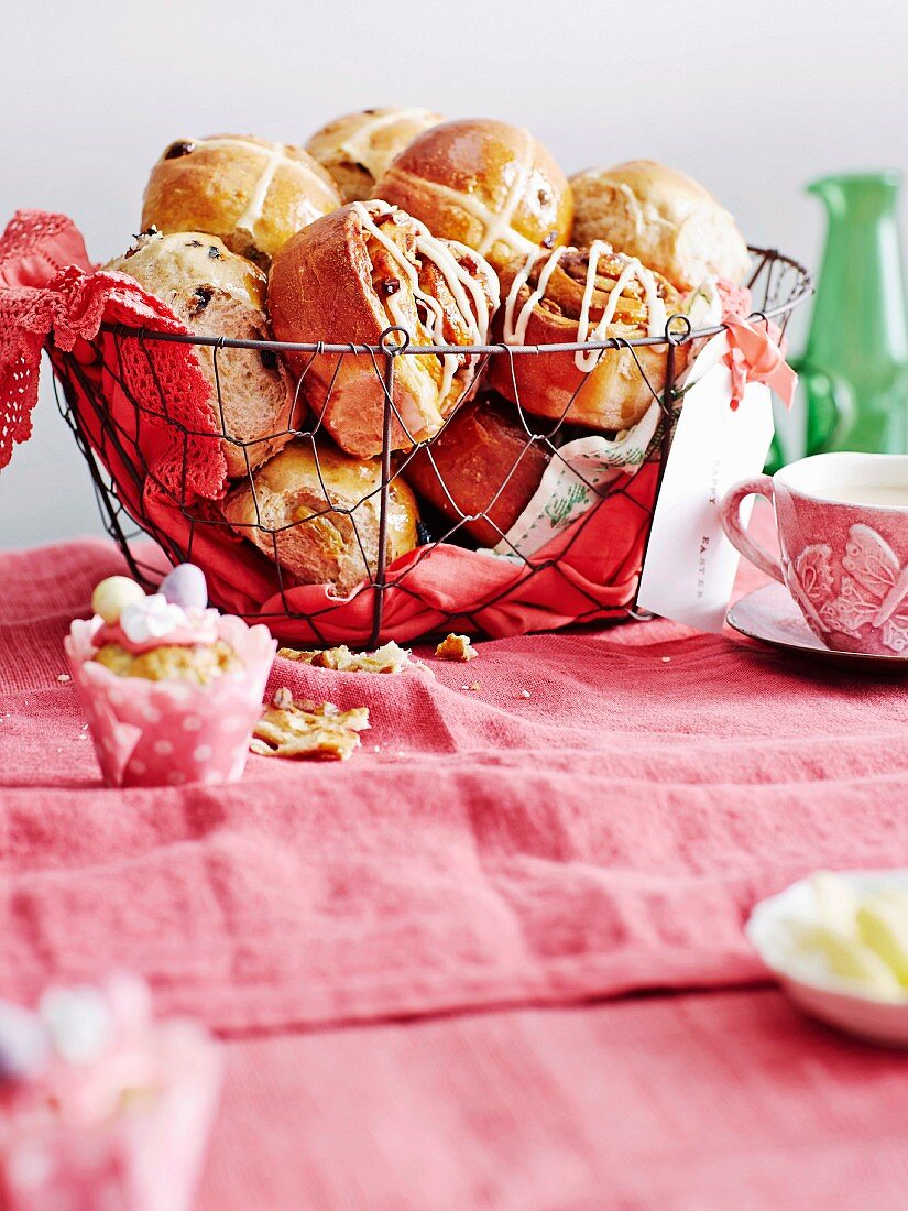 Hot cross buns and pecan buns in a wire basket, in front an Easter yeast muffin