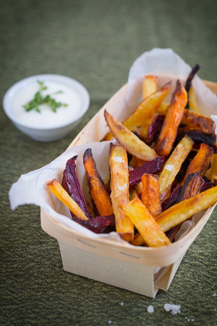 Winter vegetable chips in a wooden basket with a bowl of herb quark