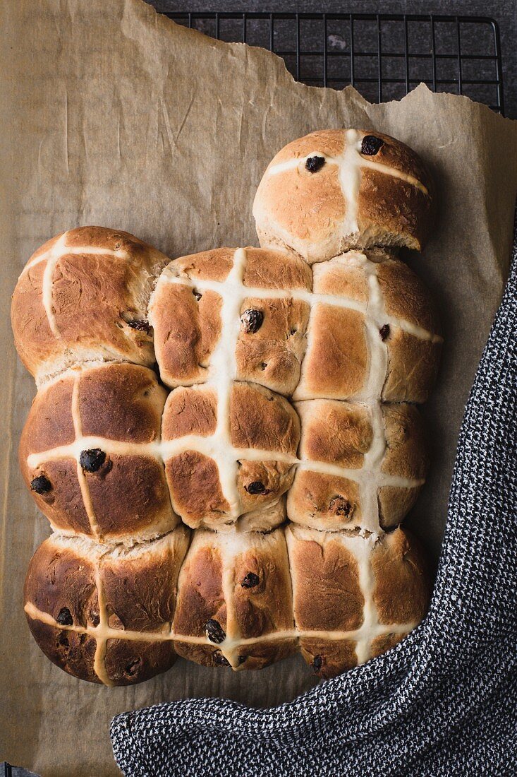 Frisch gebackene Hot Cross Buns auf Backpapier (Draufsicht)