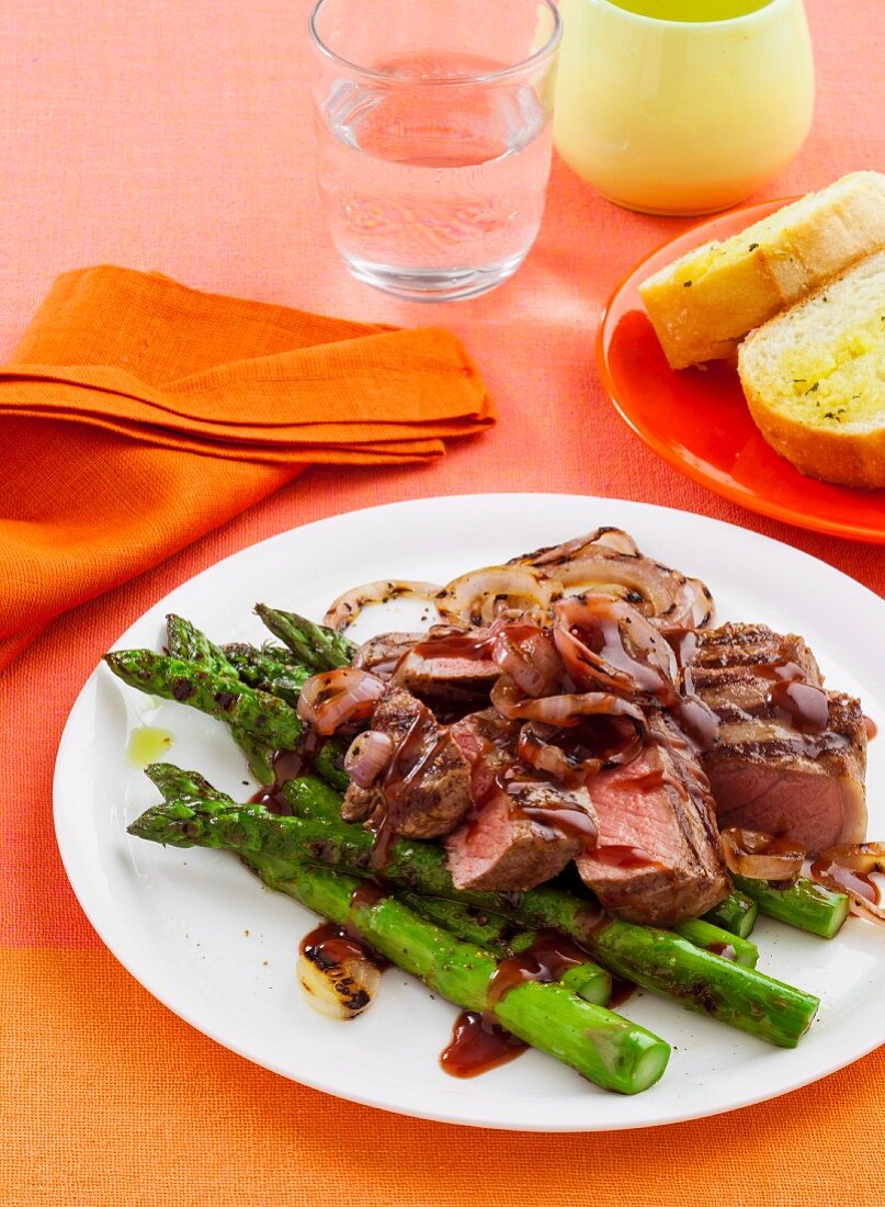 Sirloin Steak vom Grill mit Zwiebelringen und grünem Spargel