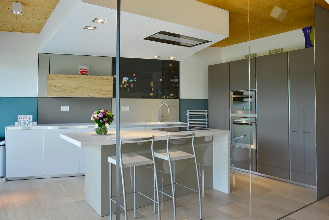 Blick durch Glasabtrennung auf Küchentheke in minimalistischer, eleganter Designerküche