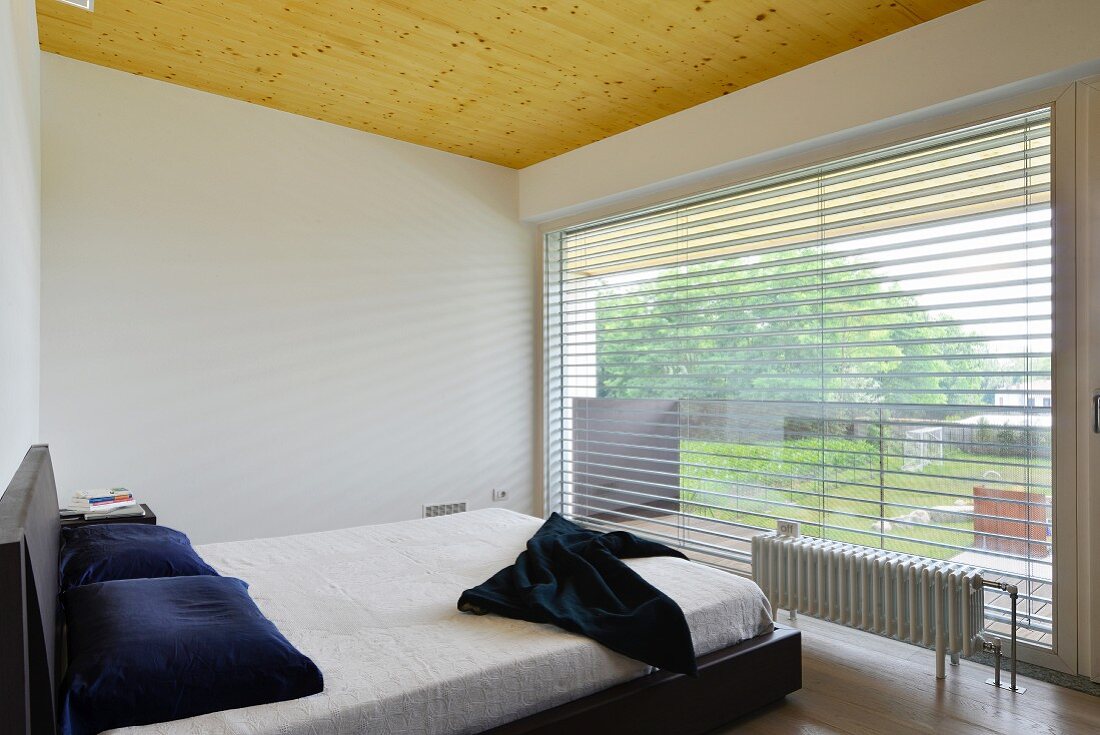 Minimalist bedroom with panoramic window and wooden ceiling