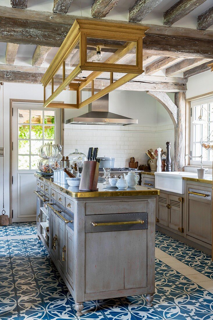 Island counter and ornate blue and white floor tiles in country-house kitchen