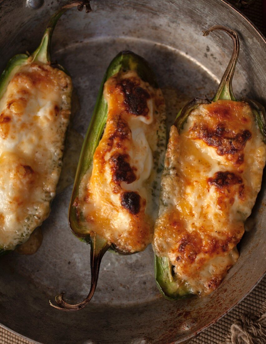 Three stuffed jalapeños in a pan (seen from above)