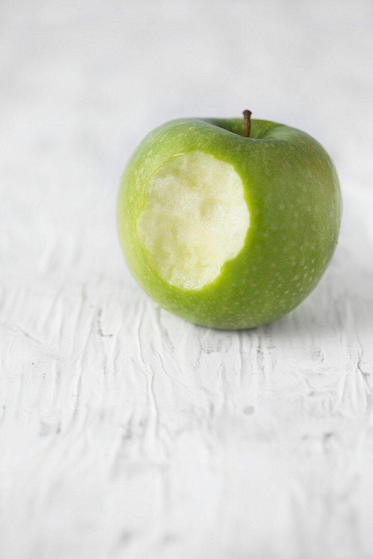 A Granny Smith apple with a bite taken out