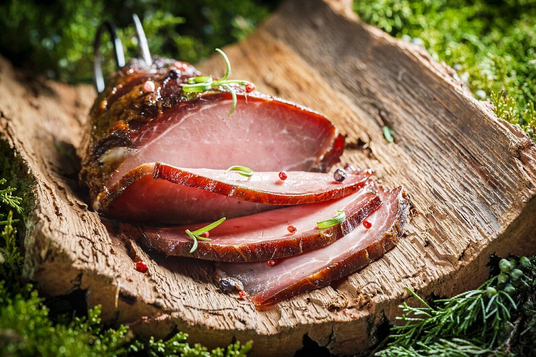 Smoked ham with herbs on a piece of bark