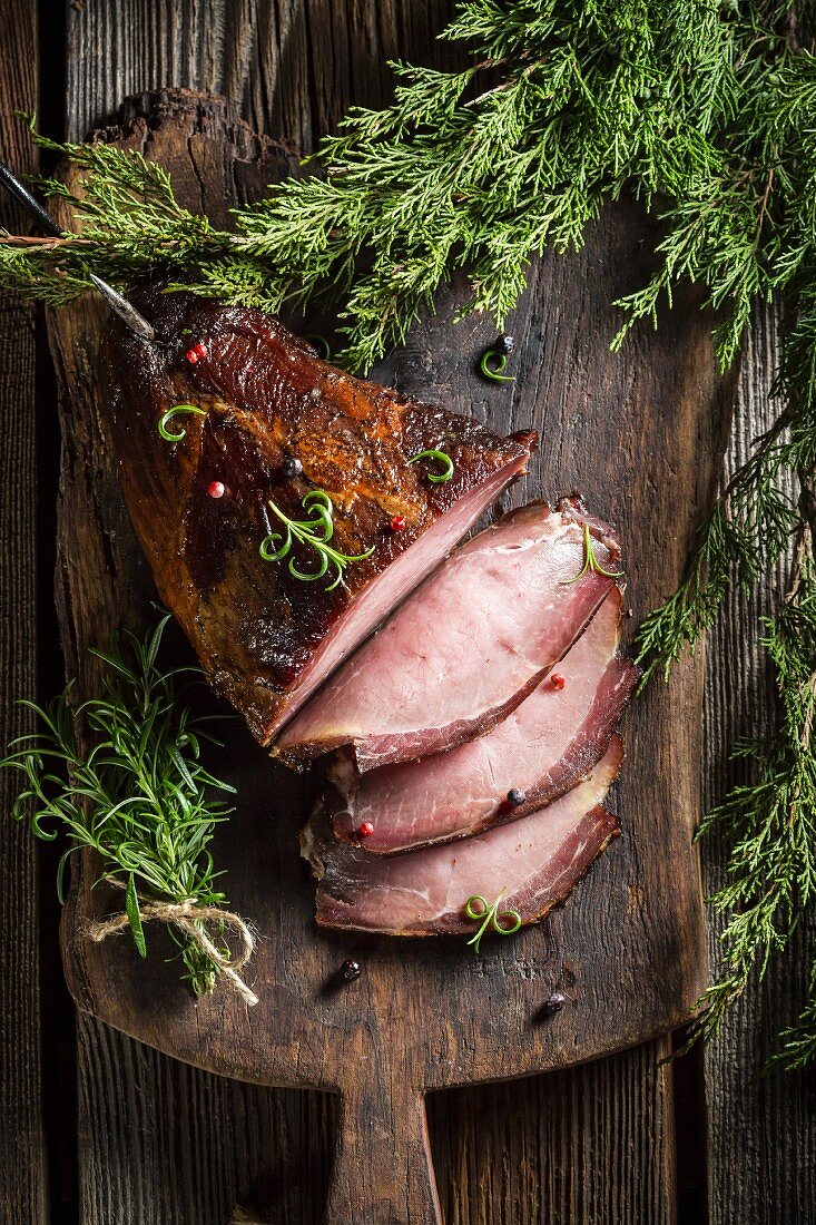Smoked ham with herbs on a wooden board