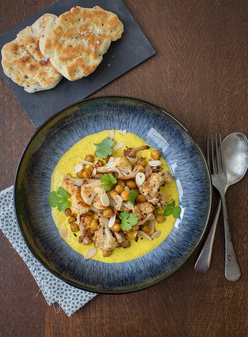 Chickpea curry with roasted cauliflower, turmeric yoghurt sauce, almonds and naan bread