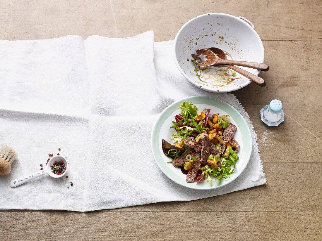 Mixed leaf salad with fresh chanterelle mushrooms and strips of steak (Paleo diet)