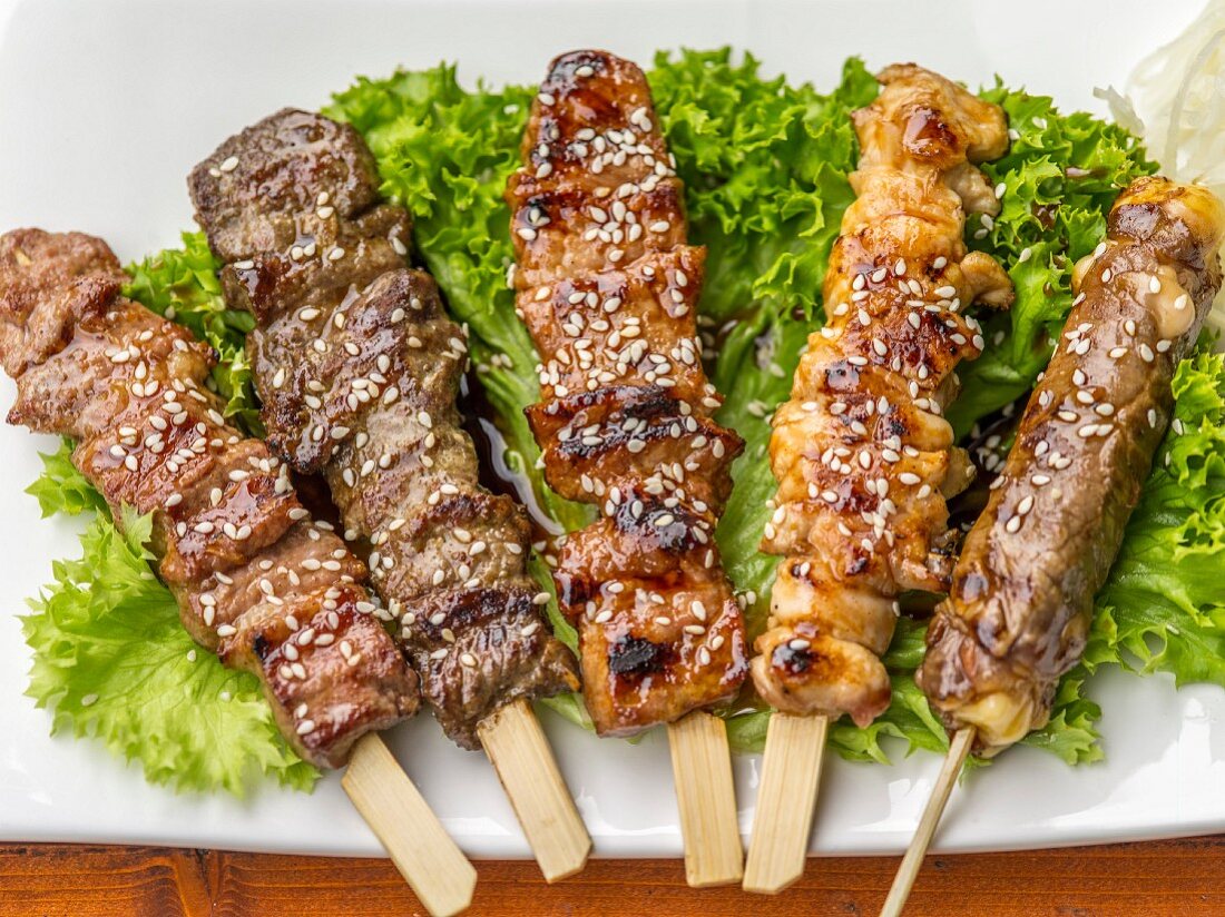 Grilled skewers with sesames seeds on lettuce leaves