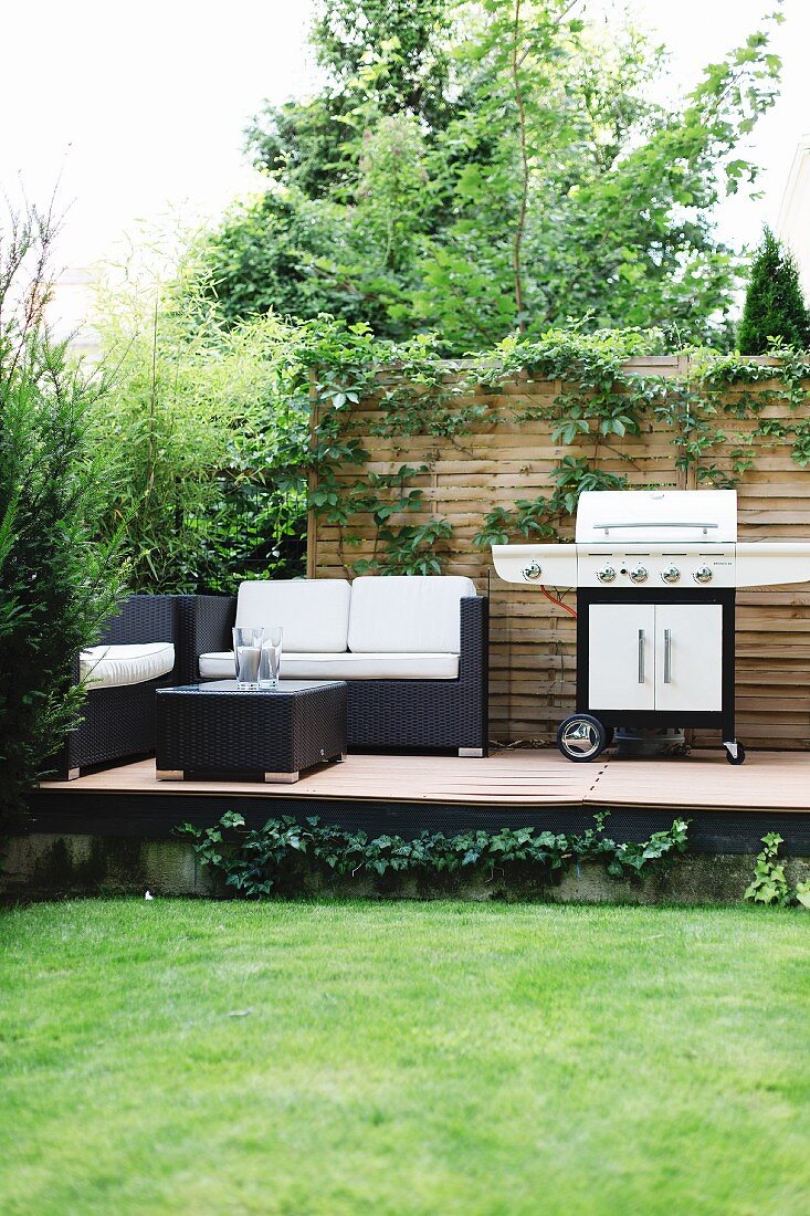 Lounge furniture and barbecue on raised terrace in garden