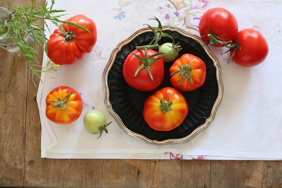 Stillleben mit selbstgezüchteten Strauchtomaten auf gestickter Tischdecke